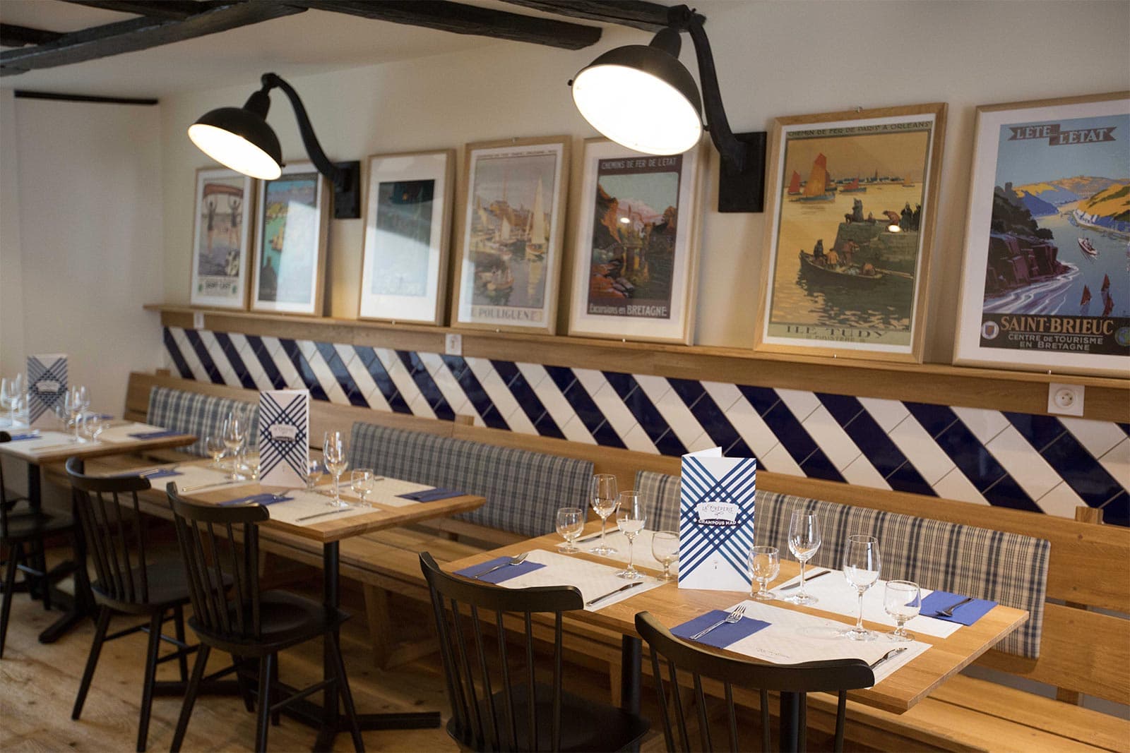 Banquettes, affiches de Bretagne et carrelage rayé bleu et blanc à la crêperie Crampous Mad